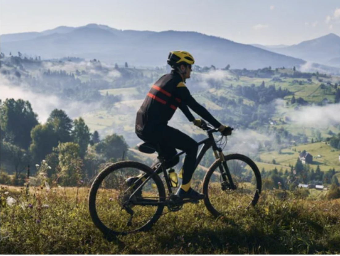 Electric mountain bike side view on countryside trail with cyclist and scenic hills