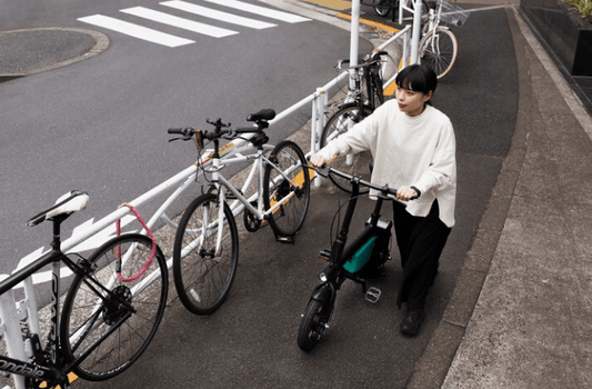 Woman walking an electric bike on urban sidewalk near other bicycles, Pogo Cycles e bikes