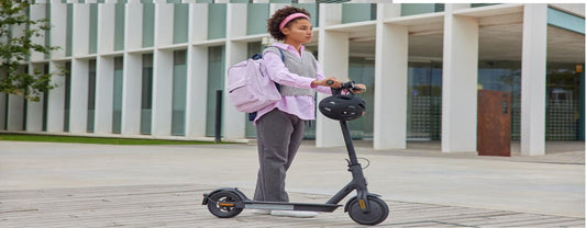 Electric scooter in black side view ridden by student outdoors in urban setting