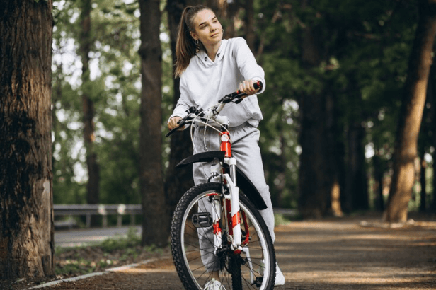 Woman with red and white electric bike on forest trail, side front view