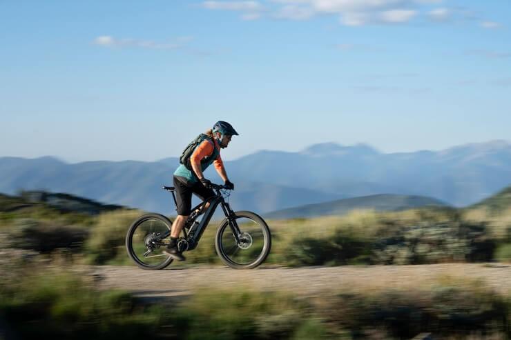 Person riding an electric bike on a mountain trail, scenic landscape, Pogo Cycles e-bike
