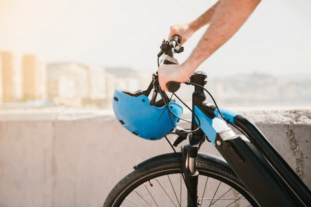 Man holding electric bike with blue helmet outdoors, Pogo Cycles e bike store
