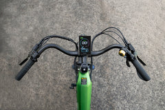 Close-up of a Cyrusher Sprint Electric City Bike in green handlebar with a digital display on a gray pavement background