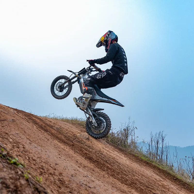 Person riding a KuKirin X1 Electric Scooter Motorcycle on a dirt hill with a clear sky background